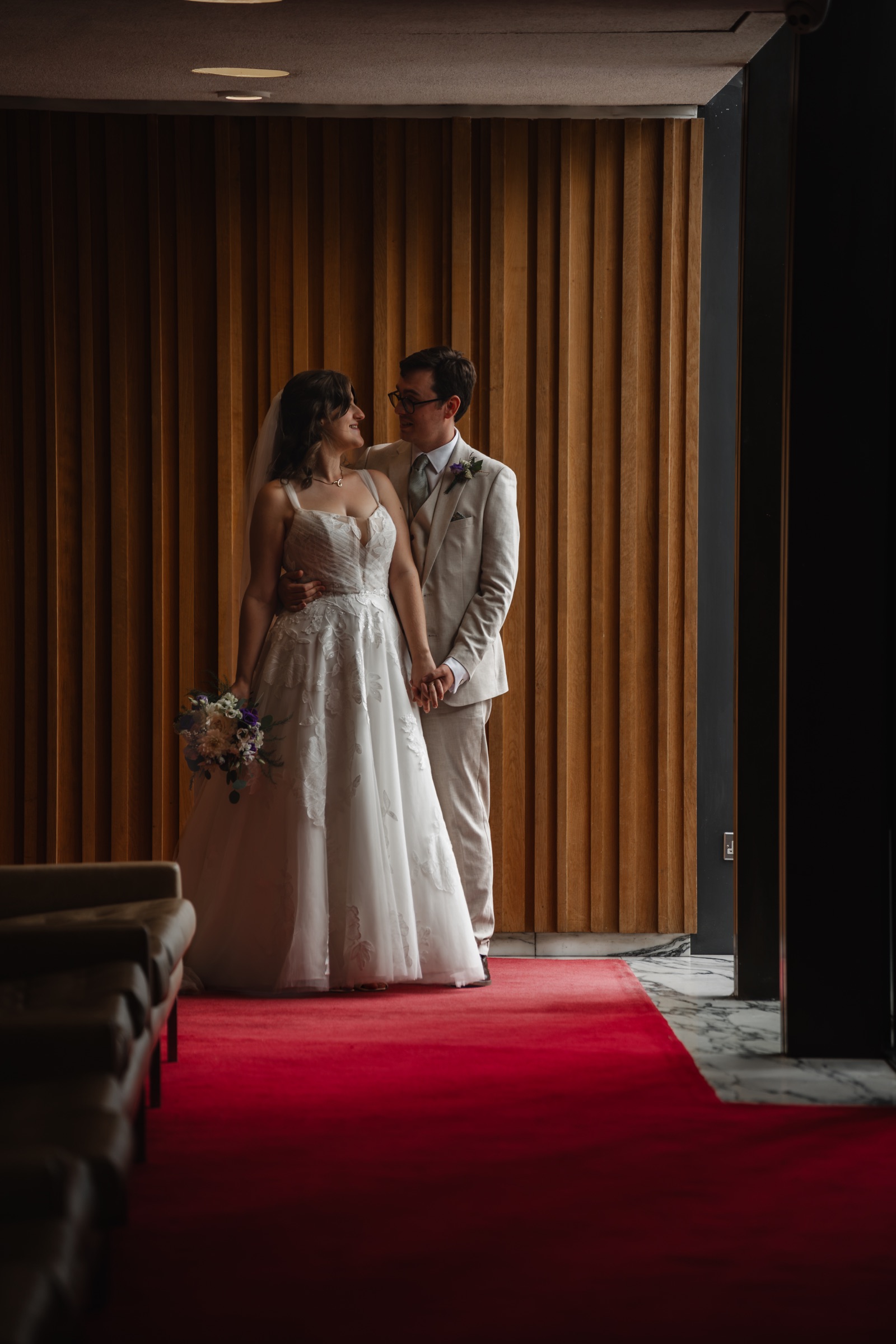 Ben and Tiffany standing together on a red carpet inside their wedding venue