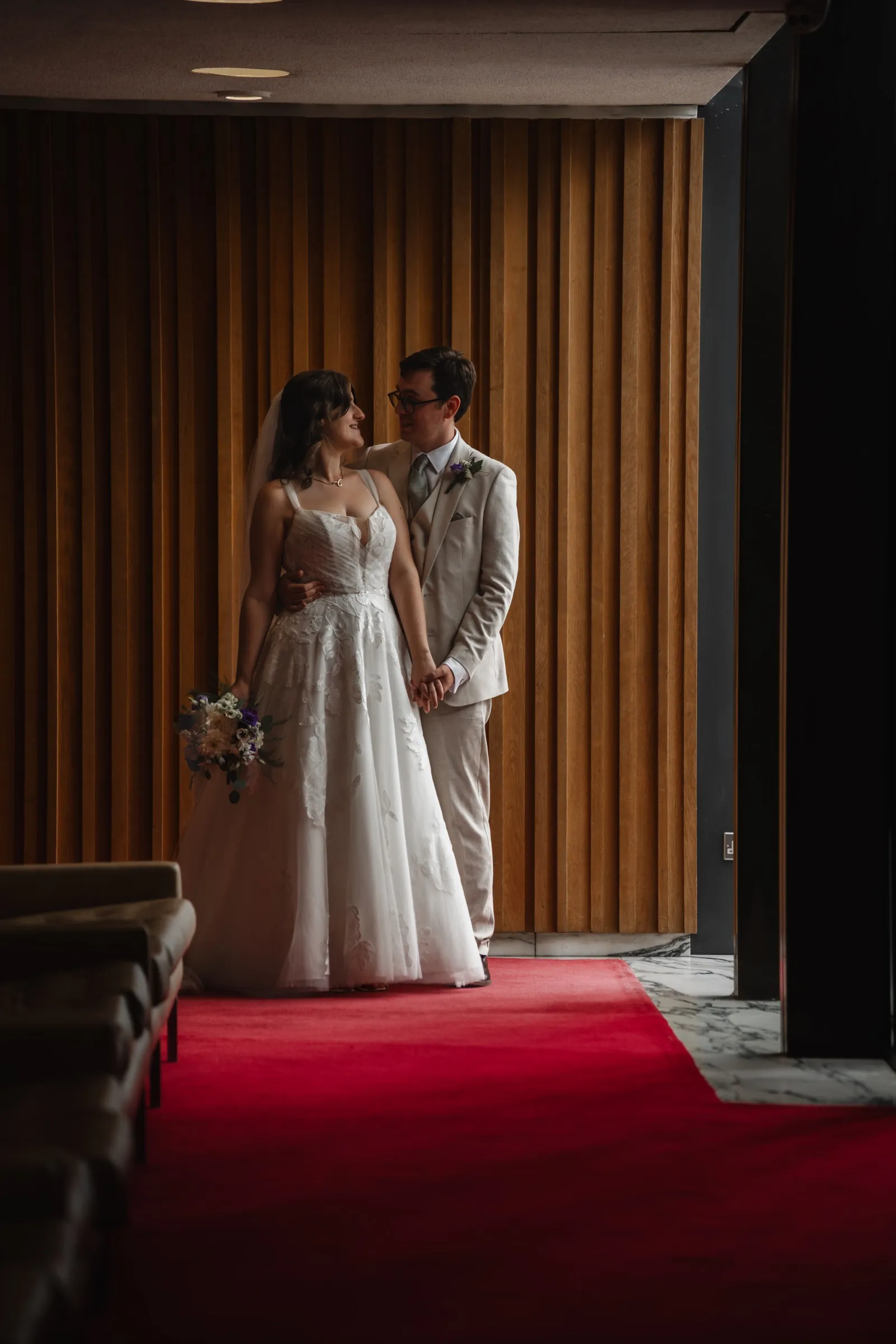 Ben and Tiffany standing together on a red carpet inside their wedding venue