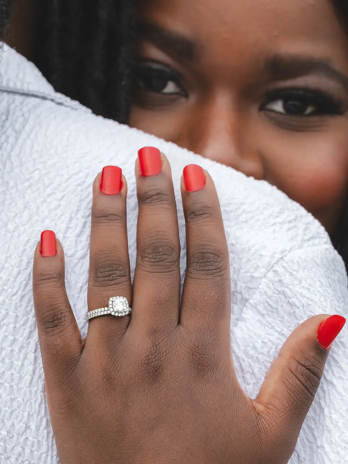 A couple embracing during an engagement shoot, with the engagement ring in focus