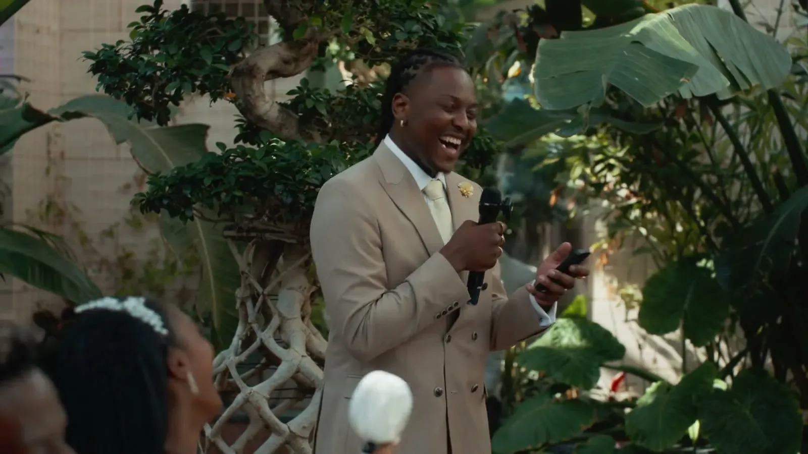 The groom laughing mid-speech, microphone in hand