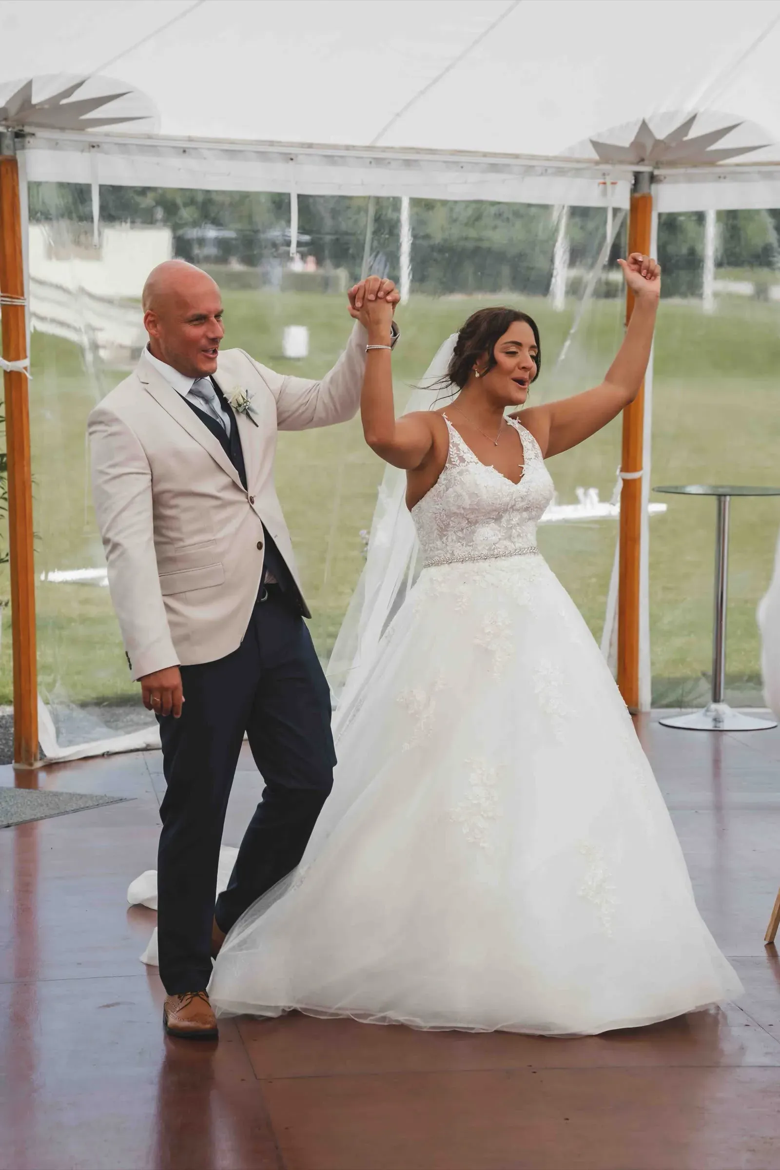 Lauren and John entering their wedding reception together with their hands raised