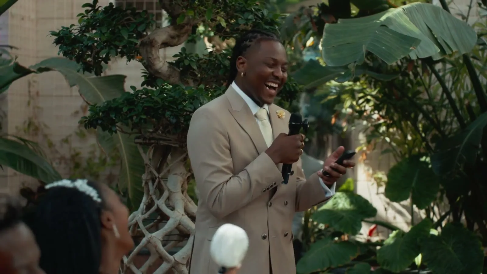 The groom laughing mid-speech, microphone in hand